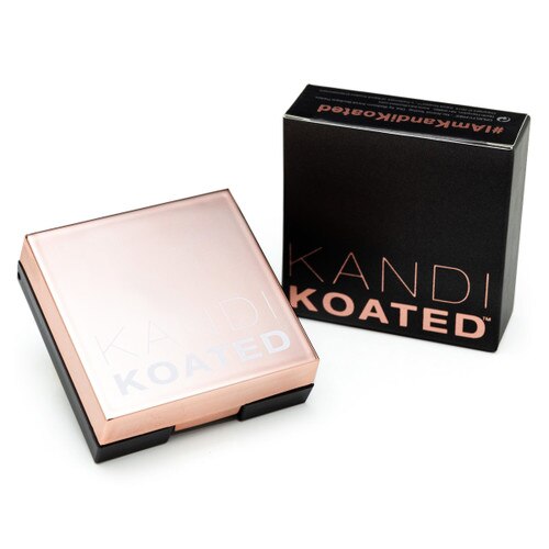 An image of a small square compact with a rose gold lid with the frosted Kandi Koated logo. Beside it is its packaging, a black box with rose gold lettering. Both sit on a white background.