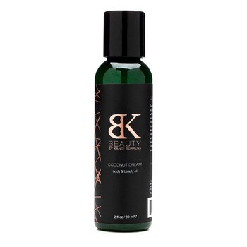 A narrow 2 ounce bottle of Coconut Dream body and beauty oil on a white background. The label is black and rose gold.