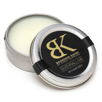 A small round tin of Enthrall Me arousal balm sits open with the lid propped against the tin on a white background. The pale surface of the balm within is visible.
