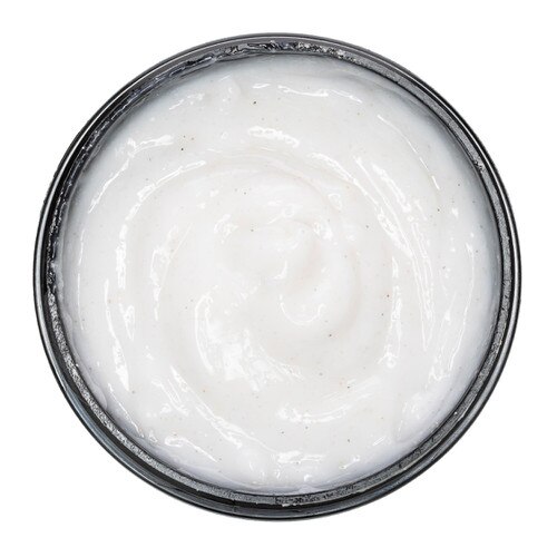 An overhead view of the creamy pale contents of the Foot Fetish Exfoliating Scrub in a black jar