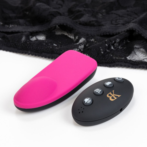 An angled close up view of the slim line Groove massager and its remote control in front of the accompanying panty on a white background.