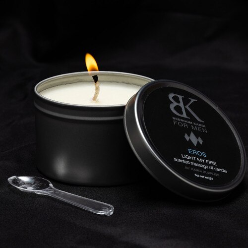 An image of the BK for Men massage oil candle in Eros lit on a seductive black background with a small spoon for the wax beside it