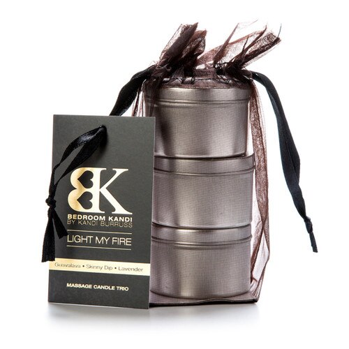 An image of three small massage oil candle tins stacked on top of each other in a black organza bag. A tag attached to the bag reads "Light My Fire" and lists the fragrances.