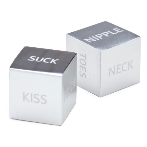A close up view of the metal dice in our Roll Play Sexy Dice set. One die has the visible words Suck, Kiss and Touch while the other visibly reads Toes, Neck, and Nipple.
