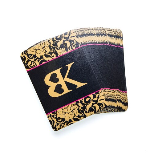 An image of the cards in Strike a Pose, face down and fanned out. The card backs are black with a gold filigree pattern on the top and bottom and the BK logo in the middle