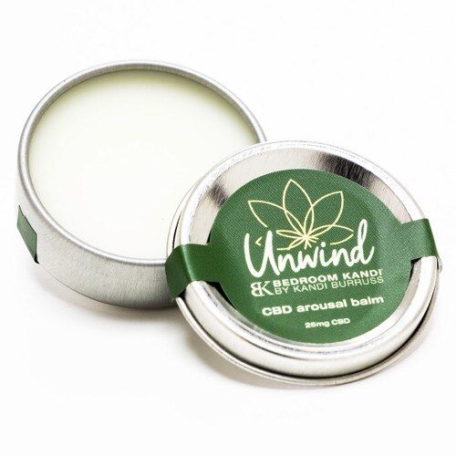The Unwind CBD arousal balm contains 25mg of CBD; the image shows the pale contents of the tin with the lid propped against it