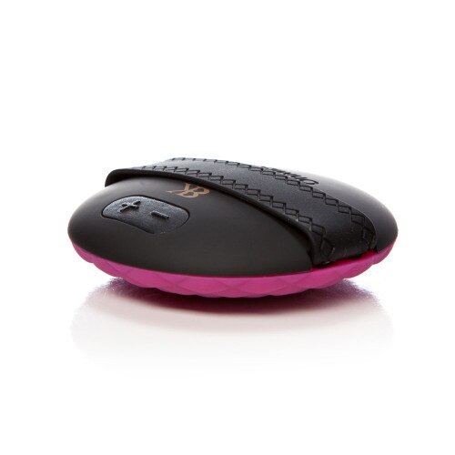 The massager component of Make Me Over sitting face down on a white surface. The back of the massager has visible controls as well as an elastic strap for easy grip.